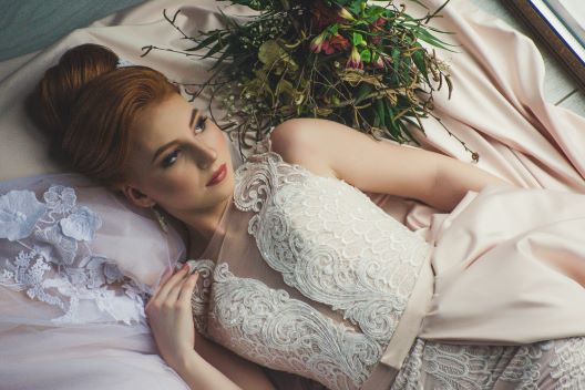 bride is lying on a floor, flowers around